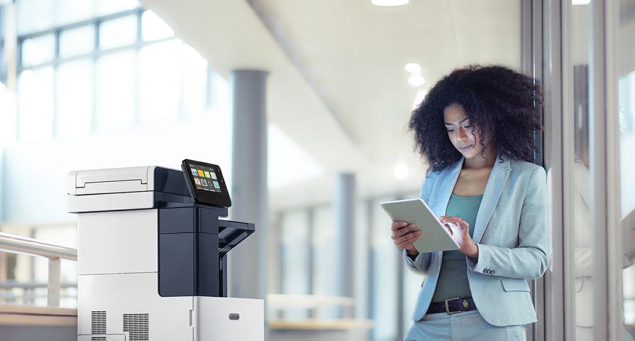B615_Office_1_mid Two women collaborating in an office using a tablet next to a Xerox VersaLink C625 multifunction printer